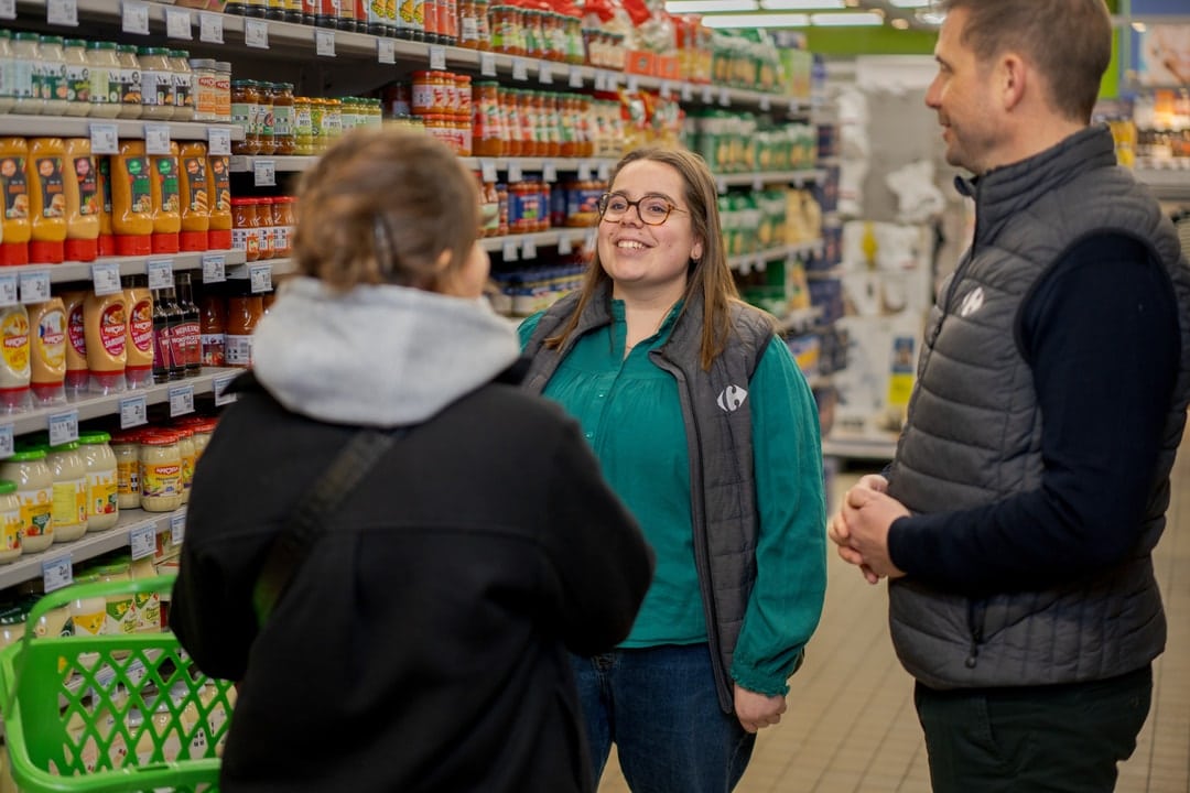 Deux collaborateurs Carrefour en train de discuter avec une cliente dans un rayon