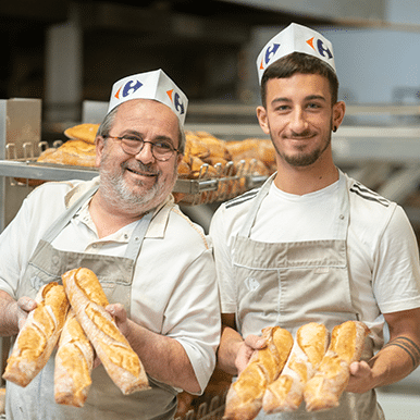 collaborateurs boulanger pâtissier qui tiennent des baguettes et du pain, avec un jeune en alternance