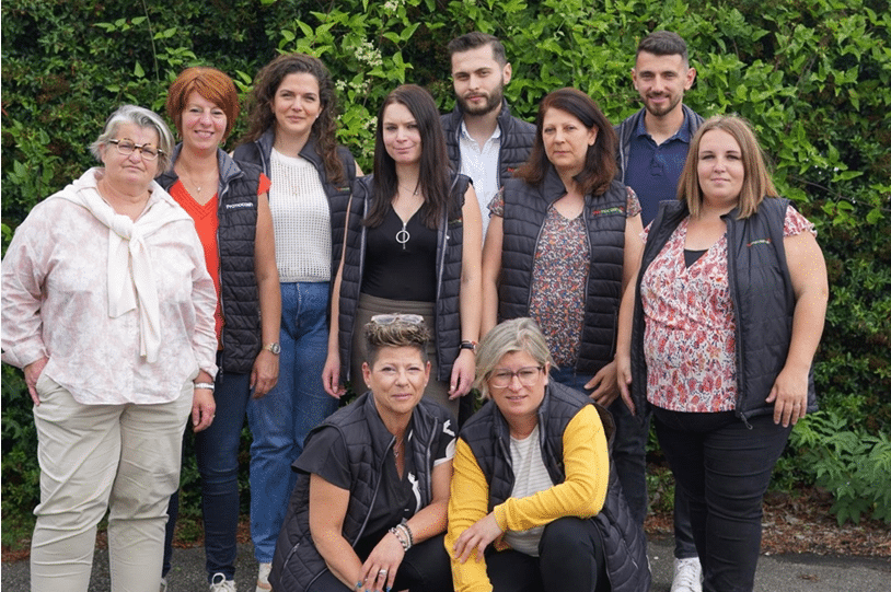 Photo de groupe de collaborateurs Promocash devant une haie