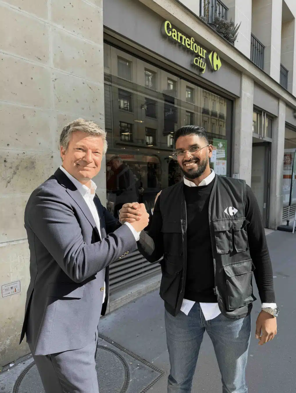 Locataire-gérant et collaborateur en train de se faire une poignée de main devant la façade d'un magasin Carrefour City