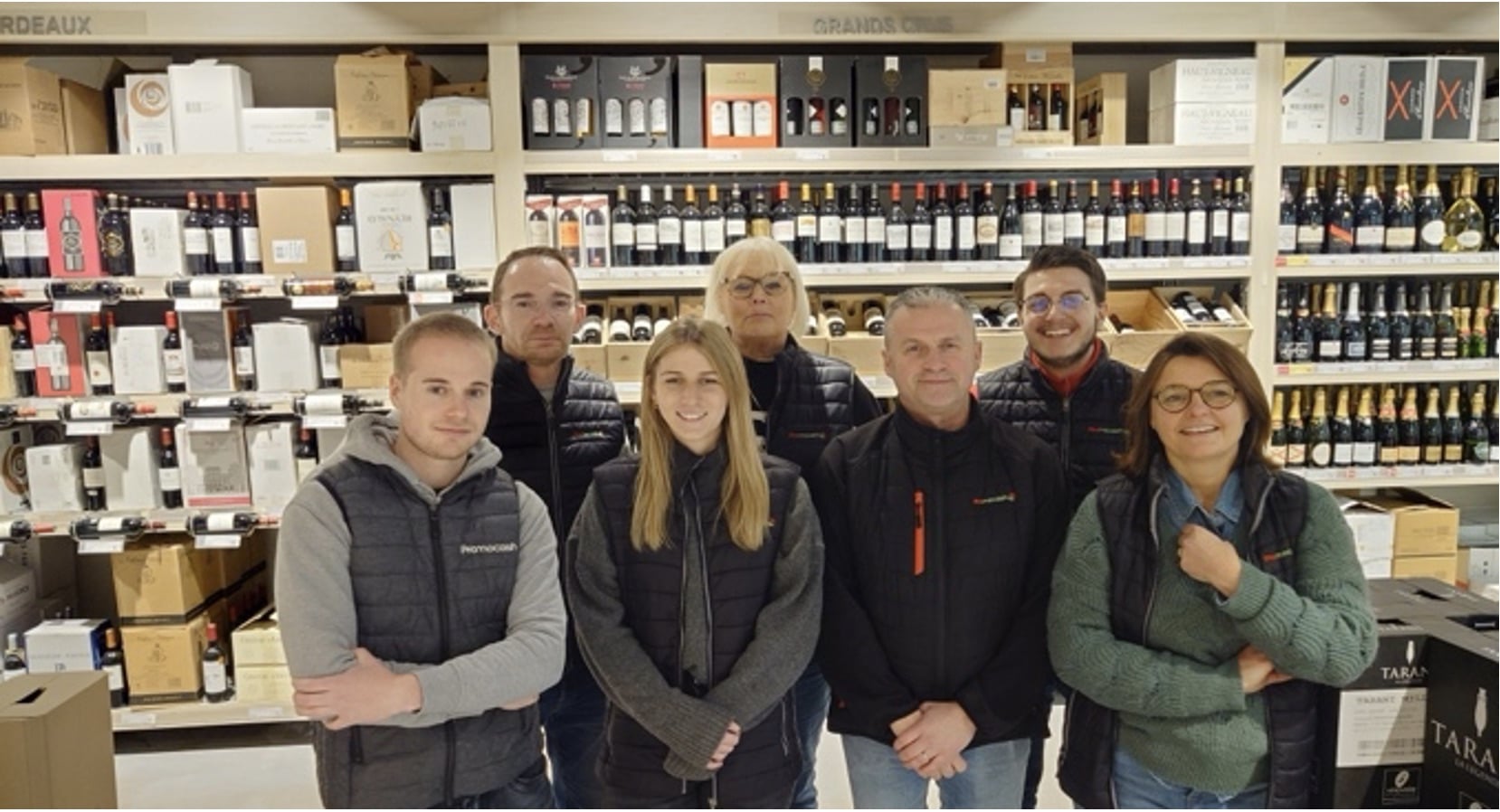 Photo de collaborateurs Promocash devant la cave à vins du magasin