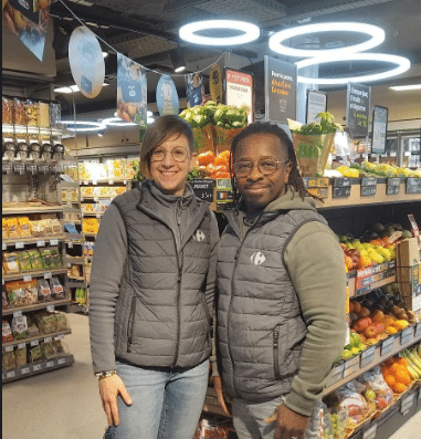 Un collaborateur et une collaboratrice Carrefour devant le rayon fruits et légumes d'un Carrefour CIty